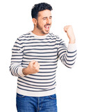 Fototapeta Natura - Young hispanic man wearing casual clothes celebrating surprised and amazed for success with arms raised and eyes closed. winner concept.