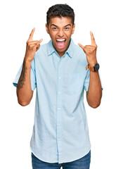 Canvas Print - Young handsome african american man wearing casual clothes shouting with crazy expression doing rock symbol with hands up. music star. heavy music concept.