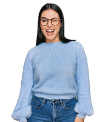 Sticker - Young hispanic woman wearing casual clothes and glasses winking looking at the camera with sexy expression, cheerful and happy face.