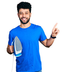 Sticker - Young arab man with beard holding electric steam iron smiling happy pointing with hand and finger to the side