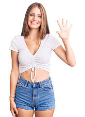 Wall Mural - Young beautiful blonde woman wearing casual white tshirt showing and pointing up with fingers number five while smiling confident and happy.