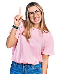 Sticker - Hispanic young woman wearing casual t shirt and glasses pointing finger up with successful idea. exited and happy. number one.