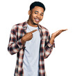 © Krakenimages.com - Young african american man wearing casual clothes amazed and smiling to the camera while presenting with hand and pointing with finger.
