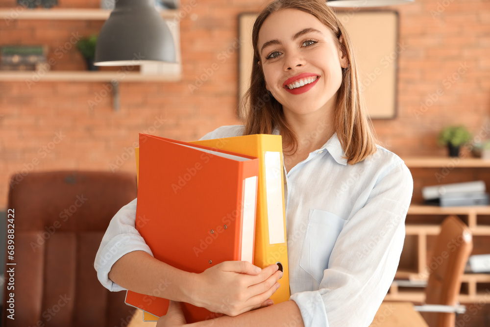 Young businesswoman with document folders in office