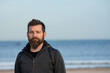 © VSzili - Portrait of man standing on sandy beach. bearded man at beach