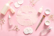 Facial sheet mask with different cosmetic products and gypsophila flowers on pink background