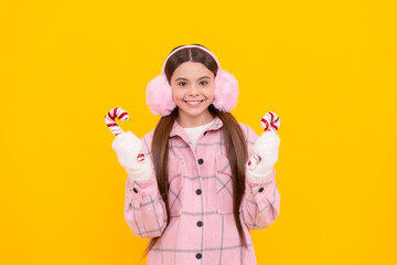 Poster - happy kid in fur earmuffs. female fashion model on yellow background.