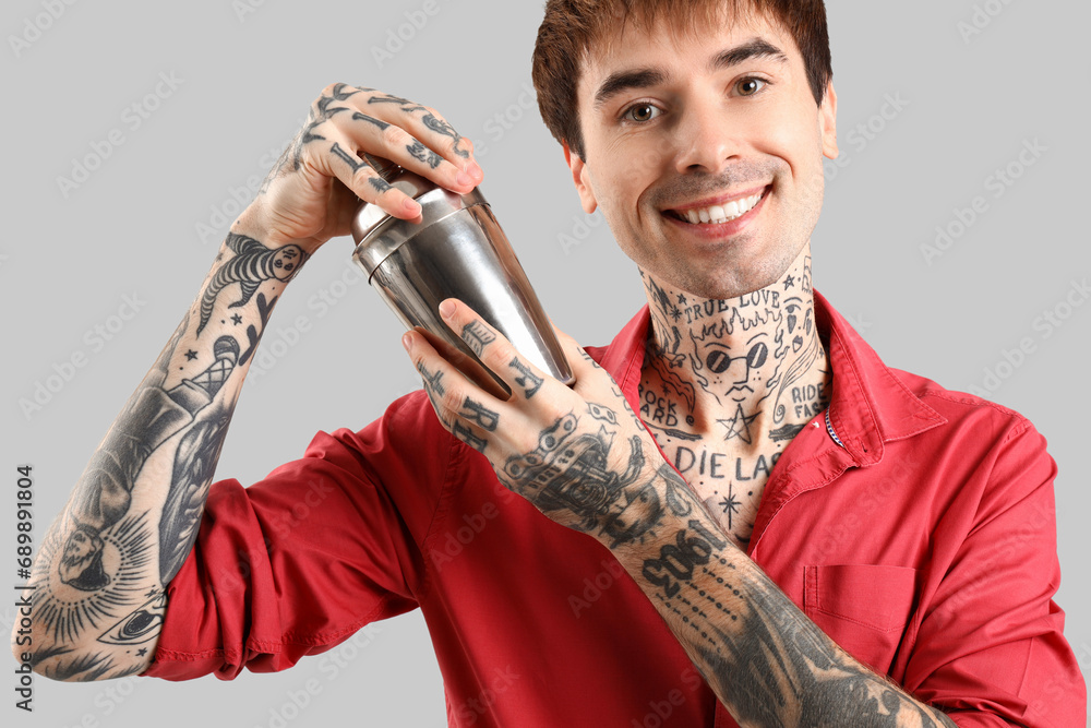 Young male bartender with shaker on white background