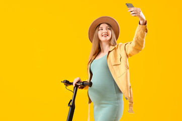 Sticker - Young pregnant woman with electric kick scooter taking selfie on yellow background