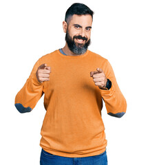 Wall Mural - Hispanic man with beard wearing casual winter sweater pointing fingers to camera with happy and funny face. good energy and vibes.