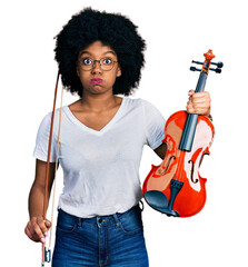 Poster - Young african american woman playing violin puffing cheeks with funny face. mouth inflated with air, catching air.