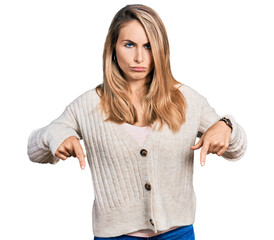 Wall Mural - Young blonde woman wearing casual clothes pointing down looking sad and upset, indicating direction with fingers, unhappy and depressed.