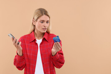 Canvas Print - Stressed woman with credit card and smartphone on beige background, space for text. Be careful - fraud