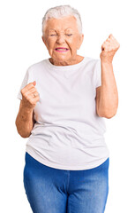 Wall Mural - Senior beautiful woman with blue eyes and grey hair wearing casual white tshirt celebrating surprised and amazed for success with arms raised and eyes closed. winner concept.