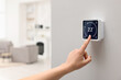 © New Africa - Smart home system. Woman using thermostat indoors, closeup