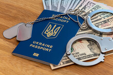 Ukrainian Passport, Military Medallion And Handcuffs Against A Background Of Paper Dollars. Concept: Crime In The Army, Bribe And Bribery, Forced Mobilization, War In Ukrvin.