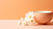A coffee cup and some white flowers on a table. Monochrome peach fuzz background.