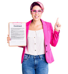 Sticker - Young beautiful woman with pink hair holding clipboard with contract document with a big smile on face, pointing with hand finger to the side looking at the camera.