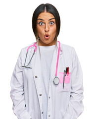 Canvas Print - Beautiful hispanic woman wearing doctor uniform and stethoscope afraid and shocked with surprise expression, fear and excited face.