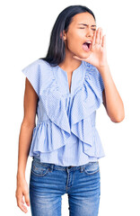 Canvas Print - Young beautiful latin girl wearing casual clothes shouting and screaming loud to side with hand on mouth. communication concept.