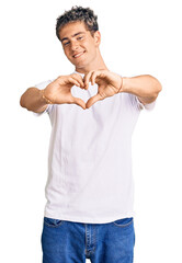 Wall Mural - Young handsome man wearing casual white tshirt smiling in love doing heart symbol shape with hands. romantic concept.