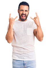 Sticker - Young hispanic man wearing casual clothes shouting with crazy expression doing rock symbol with hands up. music star. heavy concept.