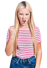 Wall Mural - Beautiful blonde woman wearing casual striped t shirt angry and mad raising fist frustrated and furious while shouting with anger. rage and aggressive concept.