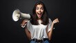 A young, shocked, excited, and happy woman wearing casual clothes, holding a megaphone