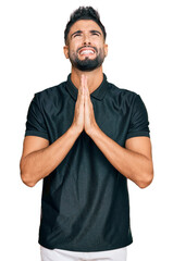 Wall Mural - Young man with beard wearing sportswear begging and praying with hands together with hope expression on face very emotional and worried. begging.