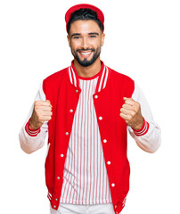 Sticker - Young man with beard wearing baseball uniform celebrating surprised and amazed for success with arms raised and open eyes. winner concept.