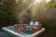 couple of men and woman in a hot tub bath in the rain forest of Vancouver Island, men and women in an outdoor bathtub in the garden of rain forest Vancouver Island Canada during sunset