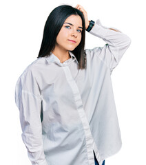 Poster - Young brunette woman with blue eyes wearing oversize white shirt smiling confident touching hair with hand up gesture, posing attractive and fashionable