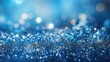 A close-up texture of blue glitter with a shallow depth of field, creating a bokeh effect with various points of light reflecting and sparkling.