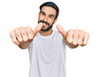 © Krakenimages.com - Young hispanic man wearing casual white t shirt approving doing positive gesture with hand, thumbs up smiling and happy for success. winner gesture.