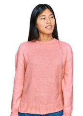 Poster - Beautiful young asian woman wearing casual winter sweater looking away to side with smile on face, natural expression. laughing confident.