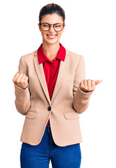 Sticker - Young beautiful woman wearing business shirt and glasses very happy and excited doing winner gesture with arms raised, smiling and screaming for success. celebration concept.