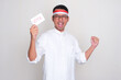 © KrishnaTedjo - Indonesian man clenching fist showing excited expression while holding election ballot