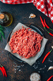 Fototapeta Uliczki - Raw minced beef meat on a tray over black background.