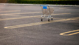 Fototapeta  -  A Lone shopping cart in an empty parking lot  in afternoon light