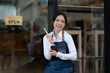 © aekachai - A young coffee shop employee is opening a shop for service.