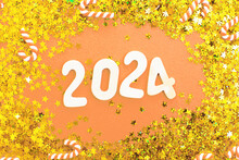 Wooden Number 2024 On Christmas Shiny Peach Fuzz Background With Sparkle Festive Golden Confetti