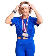 Wall Mural - Young blonde woman wearing winner medals suffering from headache desperate and stressed because pain and migraine. hands on head.