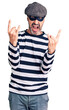 © Krakenimages.com - Middle age handsome man wearing burglar mask shouting with crazy expression doing rock symbol with hands up. music star. heavy concept.