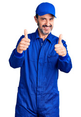 Poster - Middle age handsome man wearing mechanic uniform success sign doing positive gesture with hand, thumbs up smiling and happy. cheerful expression and winner gesture.