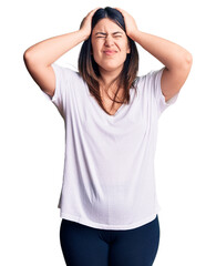 Canvas Print - Young beautiful brunette woman wearing casual t-shirt suffering from headache desperate and stressed because pain and migraine. hands on head.