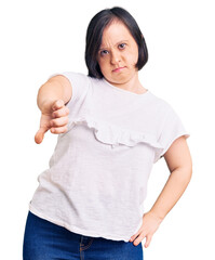 Sticker - Brunette woman with down syndrome wearing casual white tshirt looking unhappy and angry showing rejection and negative with thumbs down gesture. bad expression.