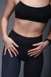 © WellStock - Close-up view of a woman wearing black sportswear. Studio shot of perfect woman figure in sport top and tight leggings