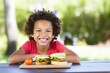 child eating sandwich at picnic table