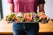 woman presenting multiple vegan tacos in a tray