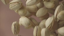Flying in air fresh raw whole and cracked pistachios on brown background. Pistachio nuts are falling in slow motion. Concept organic diet. Ungraded ProRes footage for grading